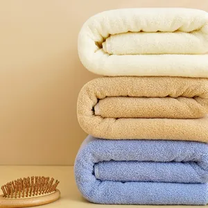 Dettaglio di tre asciugamani in cotone spesso beige, cammello e blu con anelli a spirale fitti