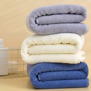 Tre spessi asciugamani in cotone in viola, blu e bianco in un cesto per il bagno