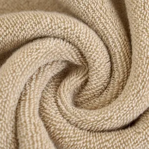 Toalla de algodón beige con textura de rizo suave y absorbente plegada en espiral