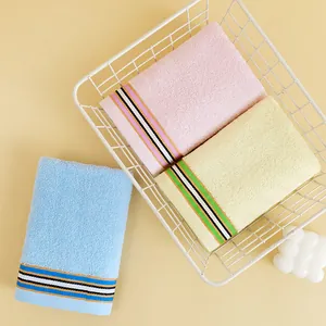 Three premium cotton towels in blue, pink, and yellow with striped hem in a basket