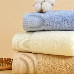 Dettaglio di morbidi asciugamani in cotone azzurro, beige e marrone con bordi a coste