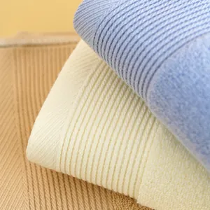 Dettaglio di asciugamani in cotone spesso in blu chiaro, crema e beige a righe