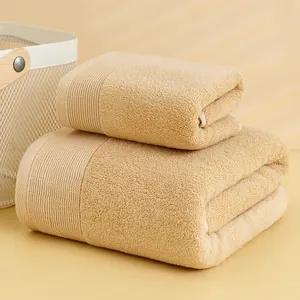Close-up of beige cotton towels with striped borders and soft woven texture details
