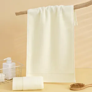 Dettaglio di asciugamani in cotone crema con bordi a costine in un ambiente spa minimale