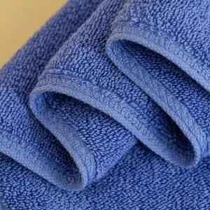 Dettaglio dell'asciugamano in cotone blu che mostra la trama a ricci e i bordi cuciti