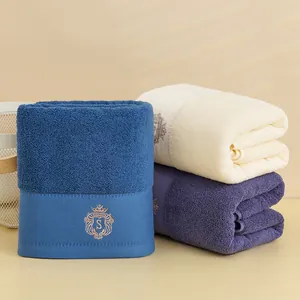 Primo piano di asciugamani in cotone spesso con elegante ricamo a corona in blu, beige e viola