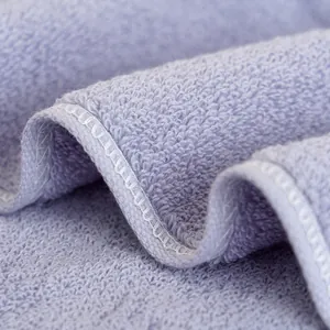 Asciugamano in cotone lilla con trama a riccio assorbente e cuciture bianche sui bordi