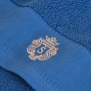 Dettaglio dell'asciugamano in cotone blu marino con ricamo a corona e lettera S
