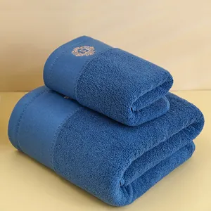 Dettaglio del ricamo corona dorata su set di asciugamani in cotone blu scuro