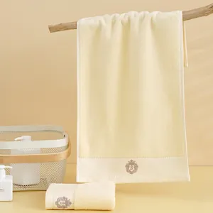 Dettaglio asciugamani in cotone beige con ricamo a corona e scudo di alta qualità