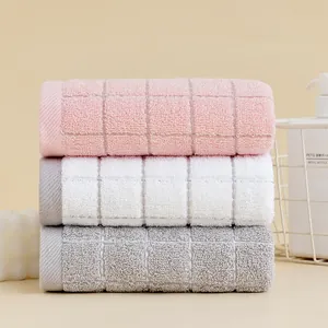 Detailed close-up of three cotton towels in pink, white, and grey with textured grid pattern