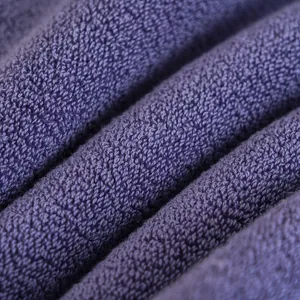 Vista macro del tessuto di un asciugamano in cotone viola con spessi anelli di spugna assorbenti