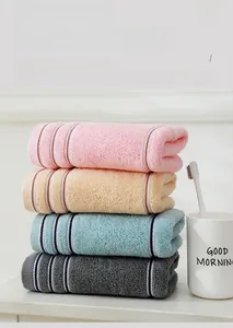 Vier gestapelte weiche Baumwollhandtücher in Rosa, Beige, Blaugrün und Dunkelgrau-Optik