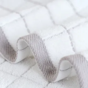 Close-up of white waffle weave cotton towel with grey textured borders and soft fibers
