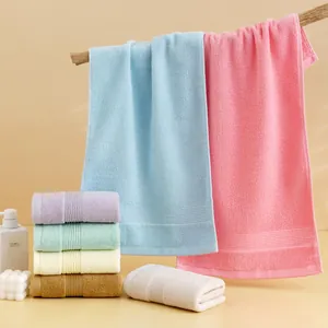 Thick absorbent cotton towels in assorted pastel colors displayed on wooden branch