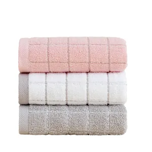Three-piece waffle weave cotton towel set in pink, white, and grey with soft texture