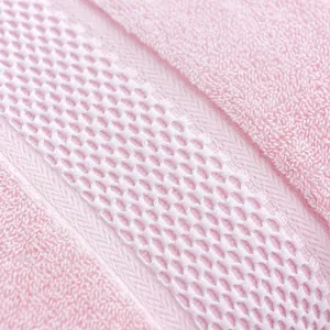 Close-up of pink cotton towel with white honeycomb weave band and durable twill edges