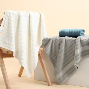 Dettaglio di asciugamani in cotone a righe nei colori bianco, grigio e blu su legno