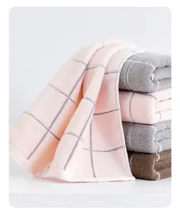Close-up of soft plaid cotton face towels in pink, grey, and brown with woven texture