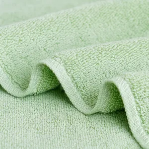 Thick light green cotton towel showing soft loop texture and durable stitched edges