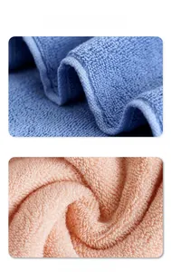 Detailed close-up of thick sky blue and coral pink cotton bath towels with hemmed edges