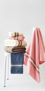 Detail of five soft cotton towels in white, pink, beige, gray, and blue with stripe accents