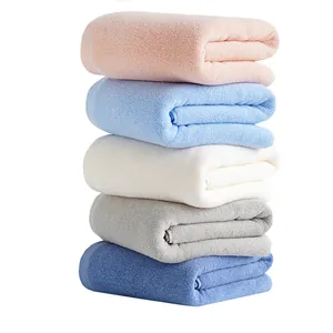 Set of five thick cotton bath towels in assorted pastel colors stacked on white background
