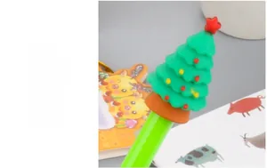 Close-up of green Christmas tree gel pen topper with colorful star on top and stationery