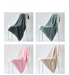 Detail of four colorful cotton towels with 3D geometric texture on white chairs