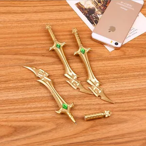 Golden metal sword-shaped gel pen set with green gemstones on wooden background