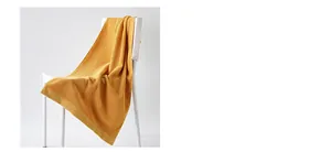 Close-up of ginger yellow cotton throw blanket with geometric knit texture on white chair
