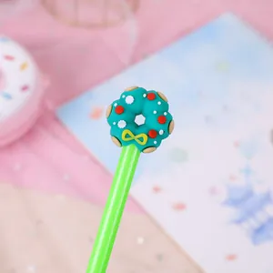 Close-up of a green donut-topped gel pen featuring a yellow bow on a pink mesh background