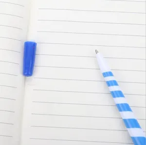 Blue and white striped Christmas magic wand ballpoint pen with cap on notebook