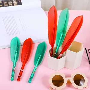 Stylos gel plumes de Noël rouges et verts avec motifs festifs sur un bureau rose