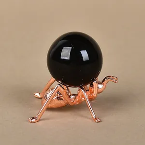 Creative rose gold ant metal stand holding a polished black crystal ball ornament