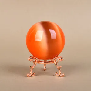 Orange cat-eye crystal ball on rose gold ornate three-legged metal display stand