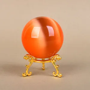 Golden ornate tripod stand holding a polished orange cat-eye crystal ball ornament