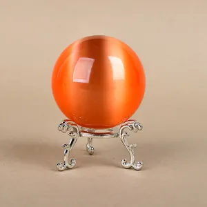 Silver vintage tripod stand holding an orange cat-eye crystal ball ornament