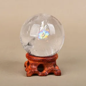 Natural clear crystal ball with rainbow ice cracks on a carved wood-style tripod stand