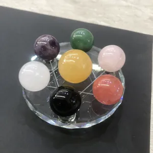 Makroaufnahme von sieben bunten Naturkristallkugeln in einer geometrischen Glasbasis