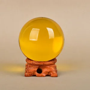 Polished yellow crystal ball on a decorative carved rosewood display stand