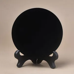 Polished black obsidian disc ornament with a minimalist display tripod stand