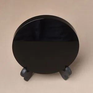 Polished black obsidian mirror disc on small stand for meditation and home decor