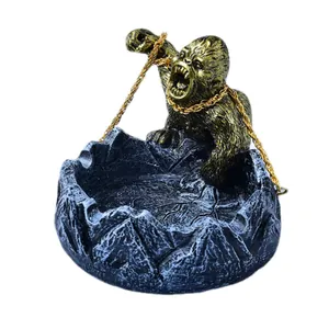 Cendrier avec statue de gorille dorée sur socle en résine noire à texture roche