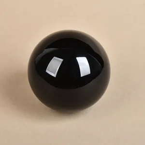 Polished black obsidian crystal ball on a minimalist khaki textured surface