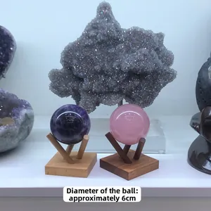Detailed view of 6cm amethyst and rose quartz crystal spheres on wooden tripod stands