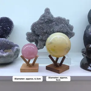 Detail view of pink and yellow crystal spheres with minimalist wooden tripod stands