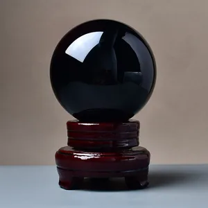 Polished black obsidian crystal ball with a deep red carved wooden pedestal base