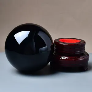 Polished black obsidian sphere on a vintage red wooden stand for home desk decor