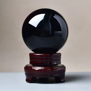 Polished black obsidian crystal ball on a vintage carved wooden stand for home decor